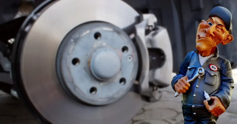 mechanic inspecting brake caliper and disc on a Ford Edge