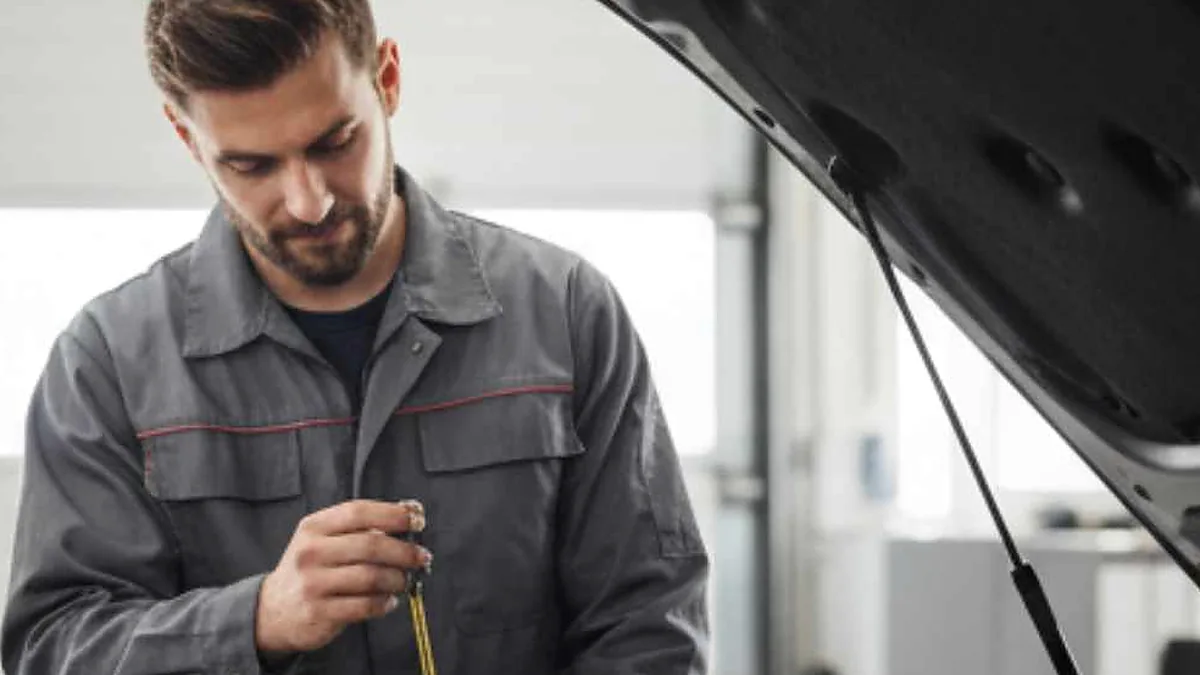 mechanic checking engine oil dipstick with the engine off