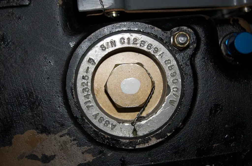 Mechanic using a digital multimeter to test a car battery under an open hood