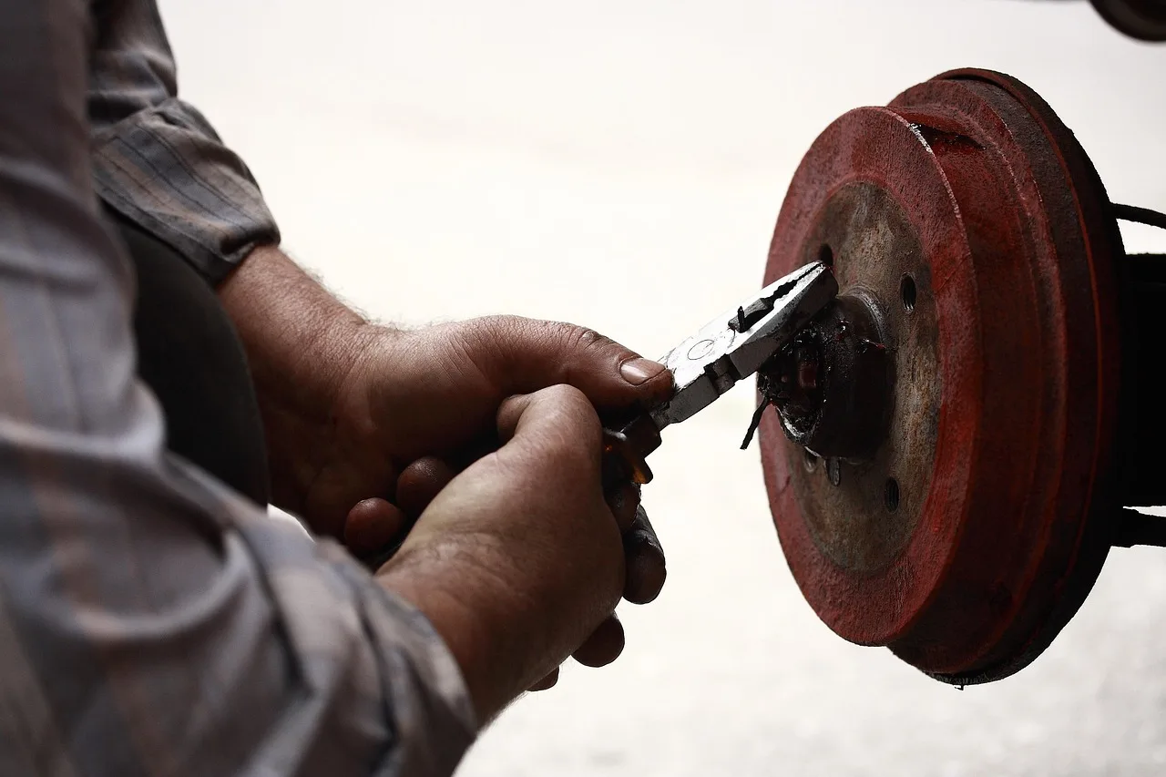 Mechanic inspecting a car brake system with wheel removed and rotor exposed in a garage