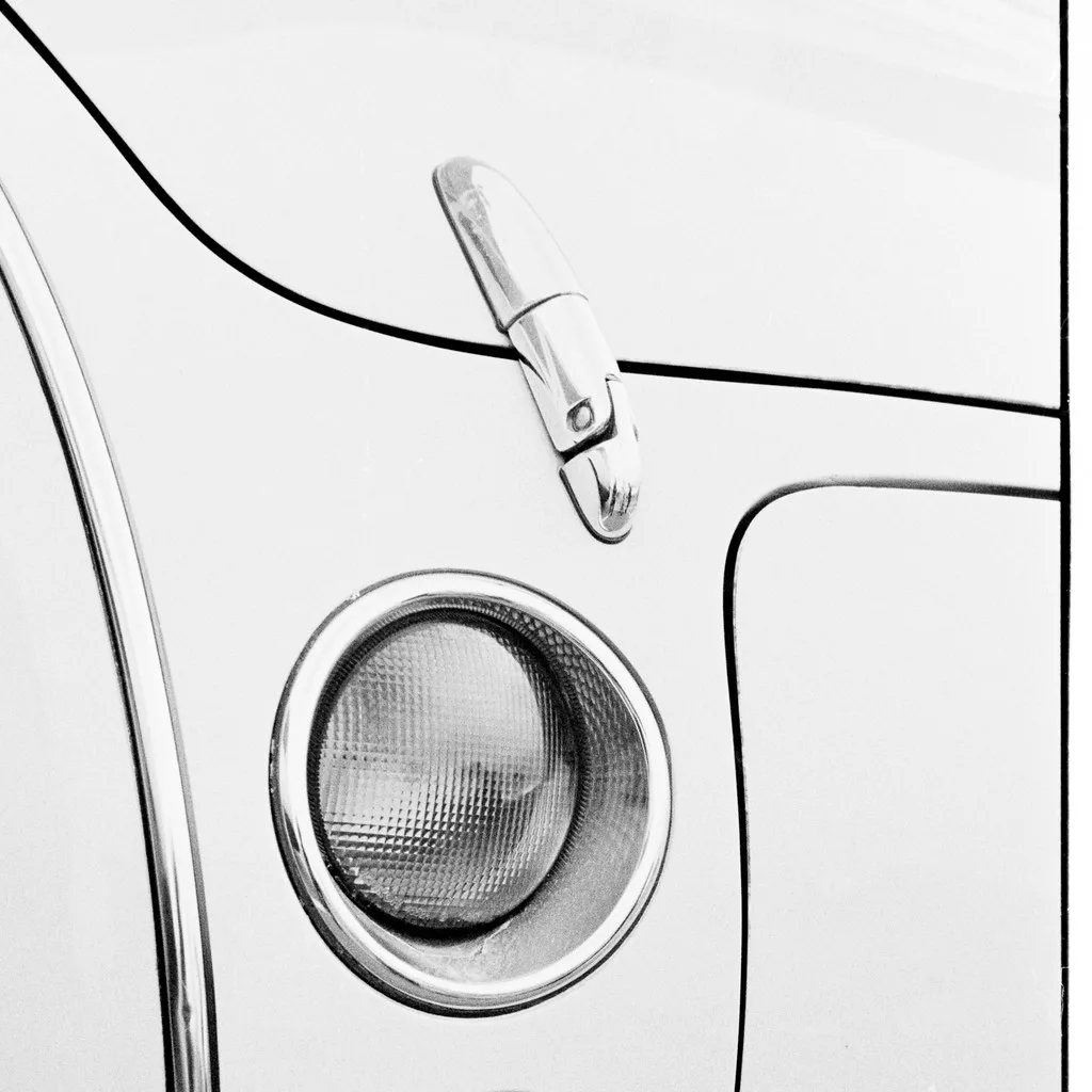 Car cleaning and restoration close-up of a hand polishing a cloudy headlight lens with a sponge.
