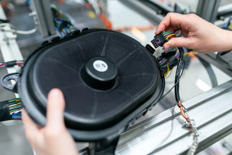 Driver checking a car battery and fuse box with a multimeter under the open hood