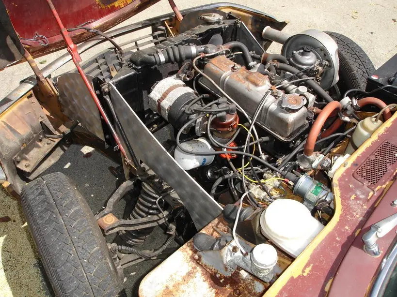 Close-up of a spark plug and ignition coil beside a car engine cylinder head