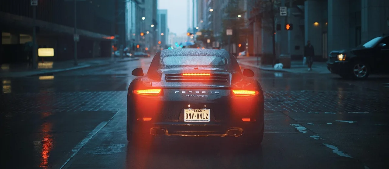 Driver checking dashboard warning lights beside a sedan at dusk