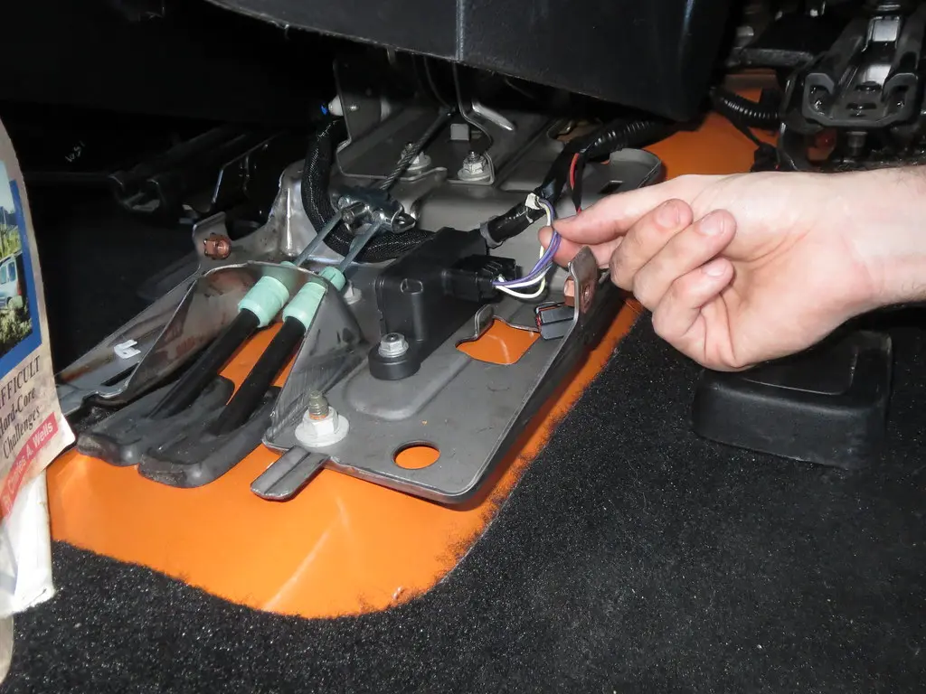 Hand inspecting a blown car bulb and fuse next to a headlamp assembly