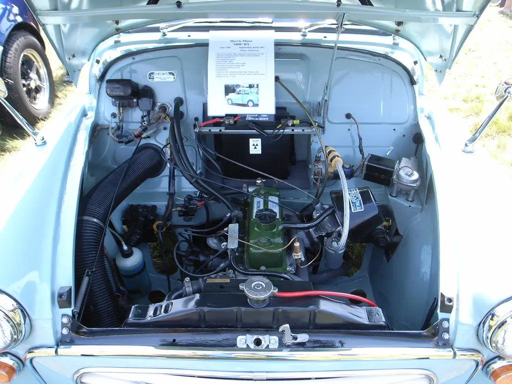 Hands diagnosing a fuel injector connector in an older engine bay