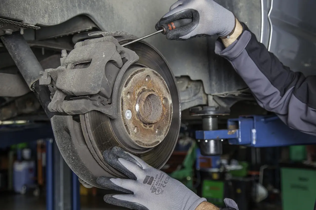 Mechanic beside a sedan with exposed brake components and an itemized brake estimate in a garage.