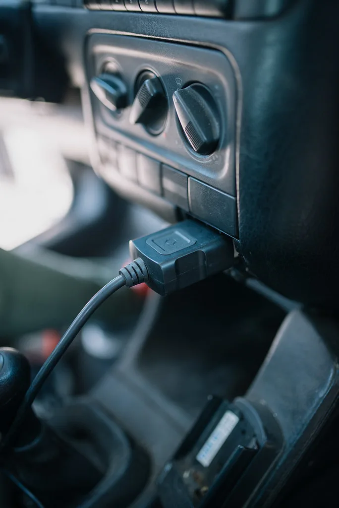 Mechanic inspecting a transmission control module beside an open car hood