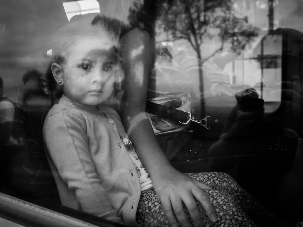 Parent fastening a toddler car seat to ISOFIX anchors in a back seat