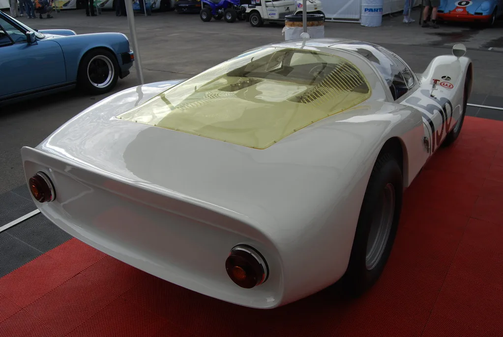 A hand points at vehicle body silhouettes beside model car shapes on a table
