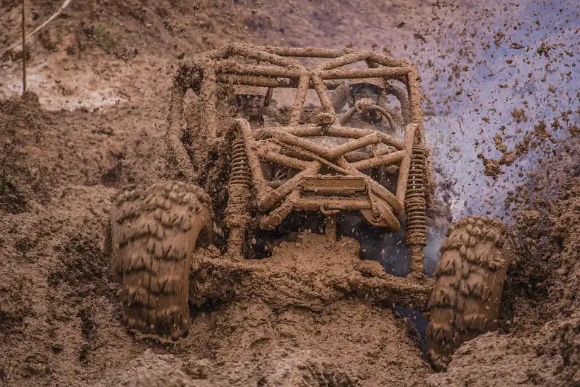 Can-Am side-by-side with upgraded wheels and tires as a mechanic checks front steering clearance
