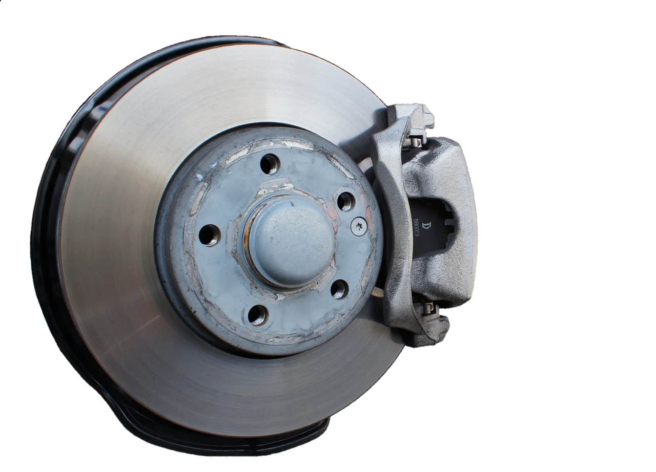 Driver beside a sedan with a wheel removed, showing brake pads and rotor in natural daylight.