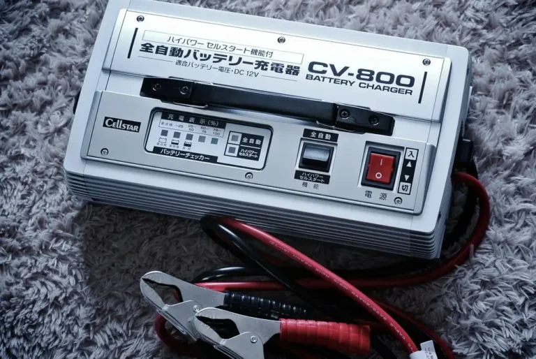 Smart car battery charger connected to a sedan battery in a garage workshop