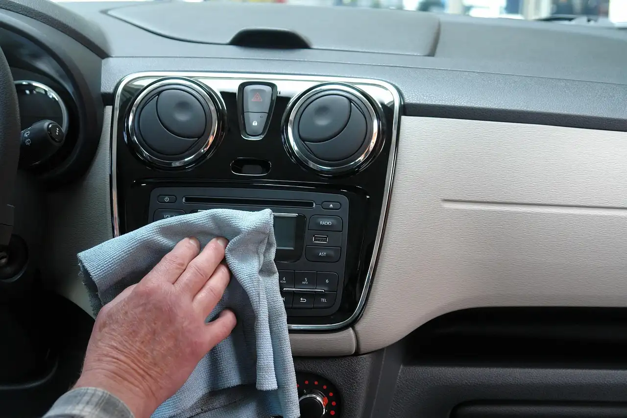Car upholstery cleaner products and tools beside a stained cloth car seat in natural light