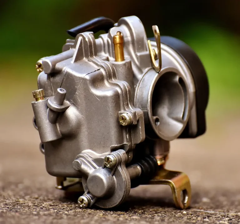 Dirty carburetor parts and cleaner cans on a mechanic’s workbench under natural light