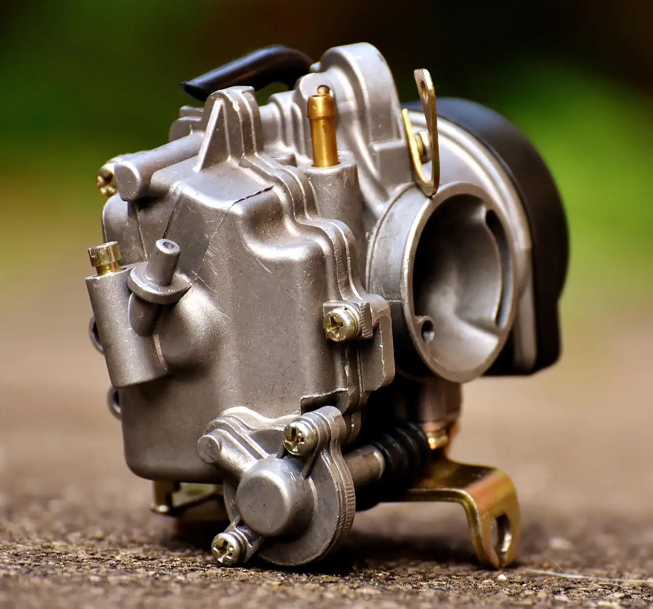 Dirty carburetor parts and cleaner cans on a mechanic’s workbench under natural light