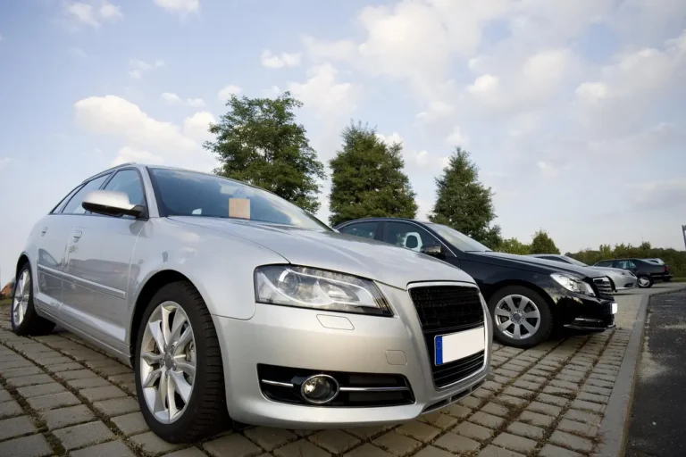 Three used cars on a dealership lot with a buyer and salesperson discussing resale value.