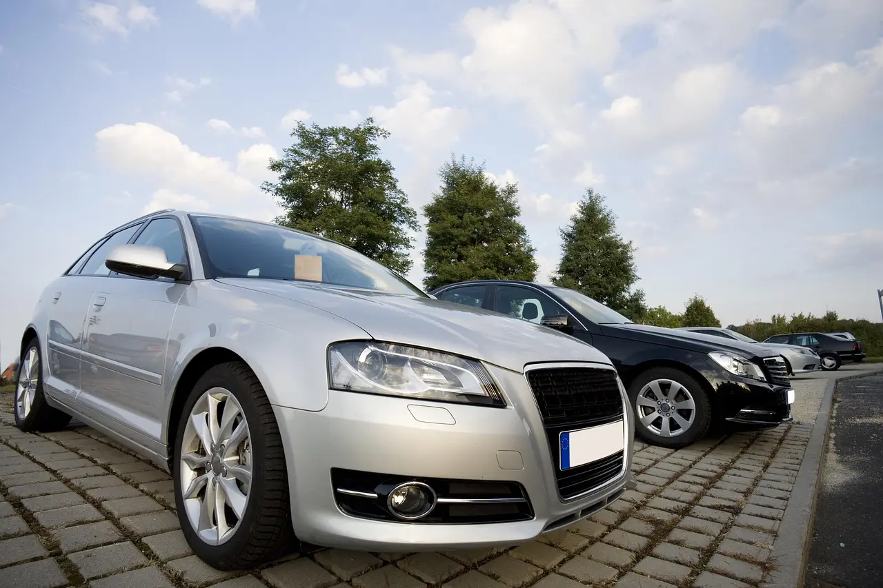Three used cars on a dealership lot with a buyer and salesperson discussing resale value.
