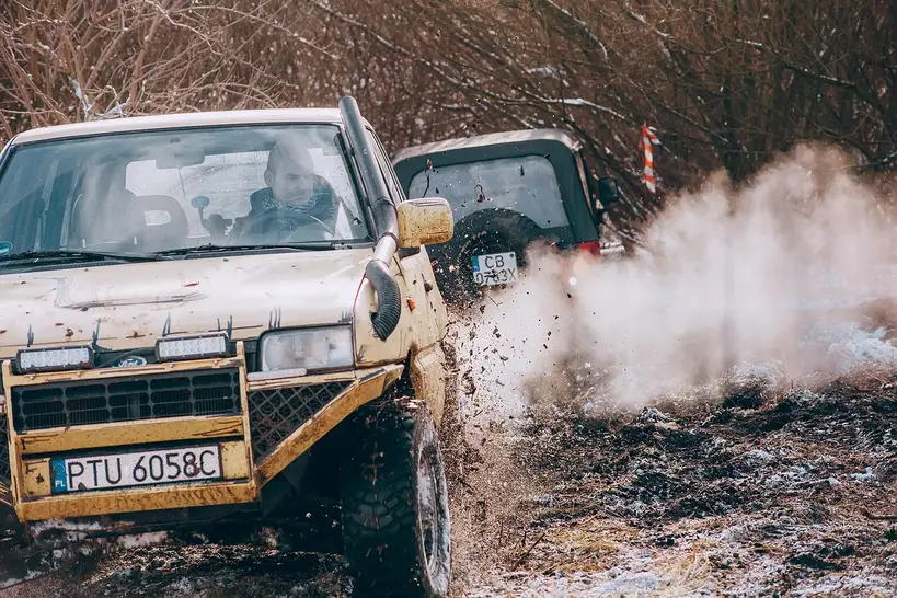 Compact crossover on a rough gravel road, showing suspension travel, tires, and ground clearance
