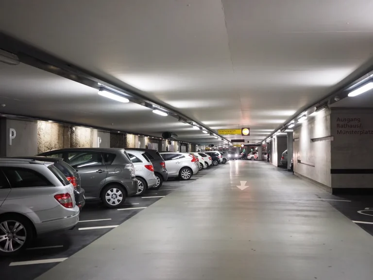 Small hatchback fitting into a tight city parking space between two cars.
