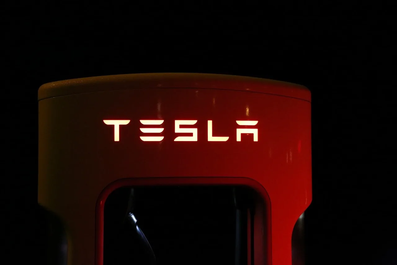 Electric car parked in a driveway beside a charging cable on a quiet suburban morning