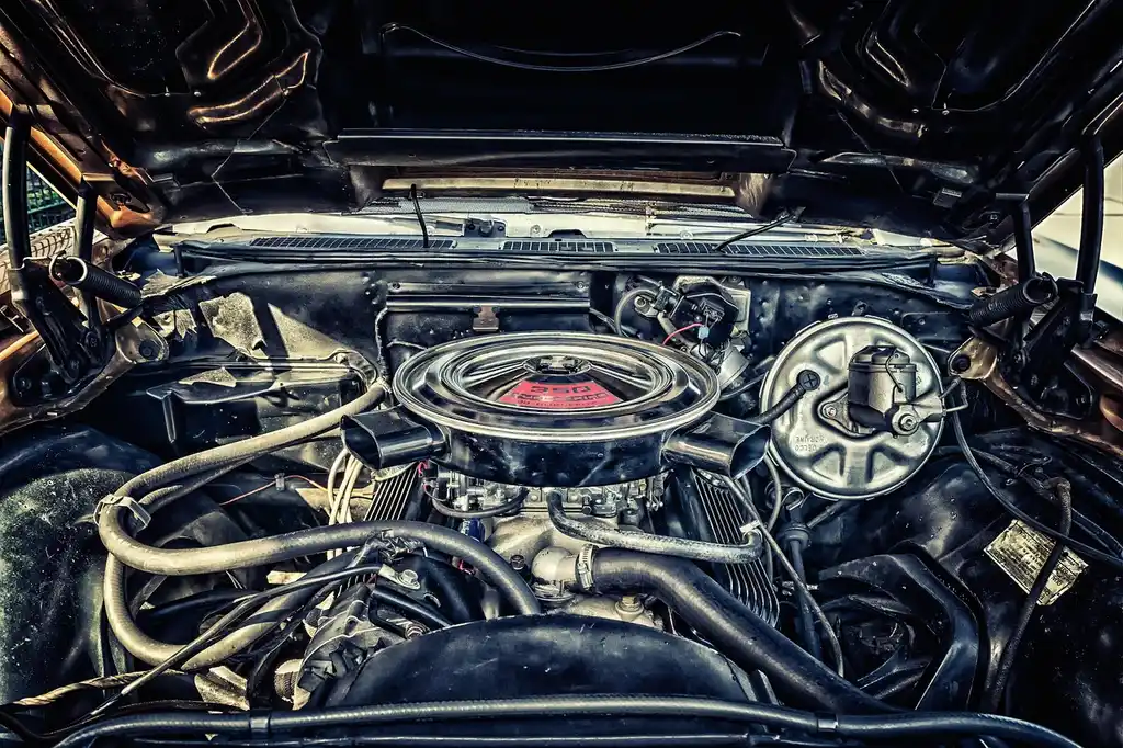 Mechanic inspecting a high-mileage car engine with the hood open in a repair bay