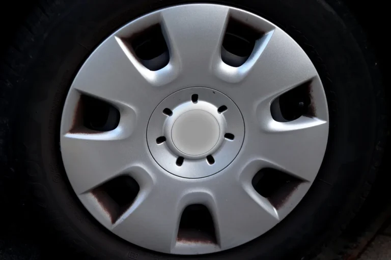 Three wheel cleaner bottles beside a brake-dusted alloy rim and microfiber mitt