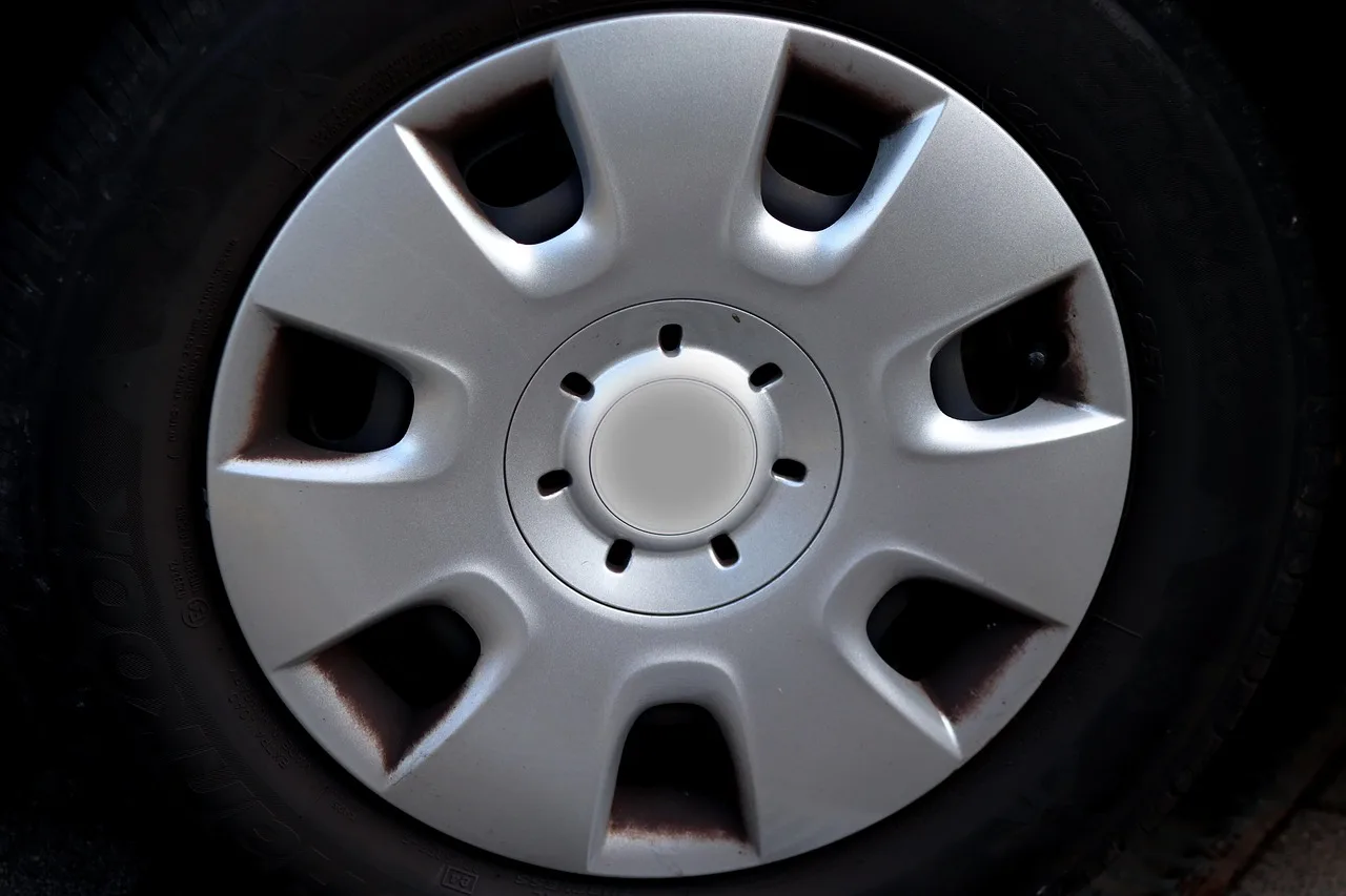 Three wheel cleaner bottles beside a brake-dusted alloy rim and microfiber mitt
