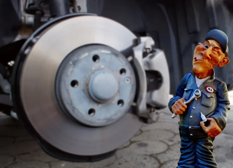 Mechanic inspecting car brake pads and rotor through a wheel on a lifted sedan