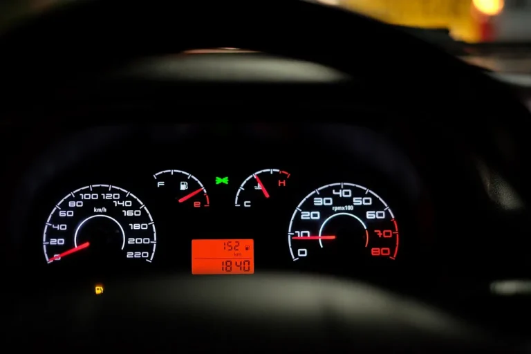 Car dashboard lights glowing while a driver checks the warning symbols at dusk