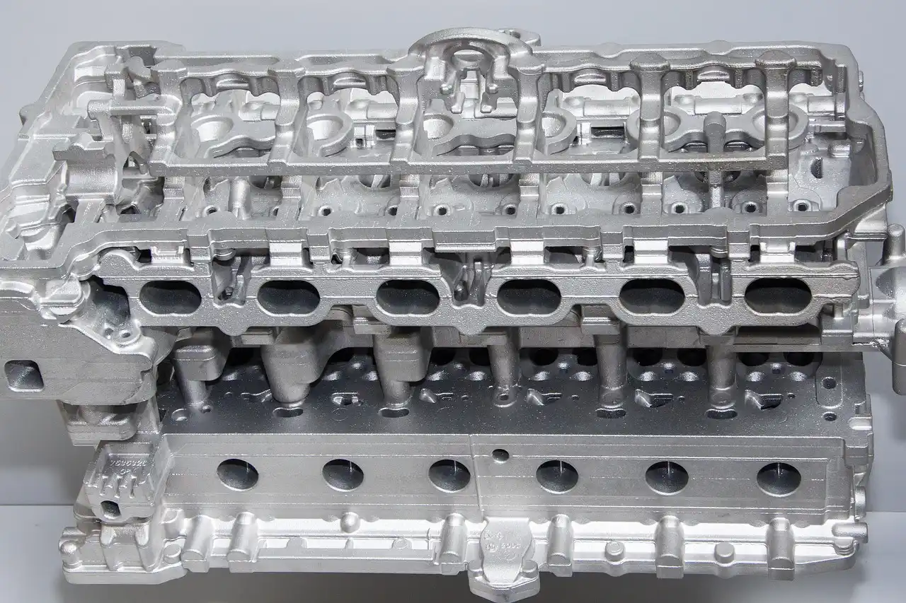 Open car engine bay with visible belts, hoses, battery, and engine cover under natural light