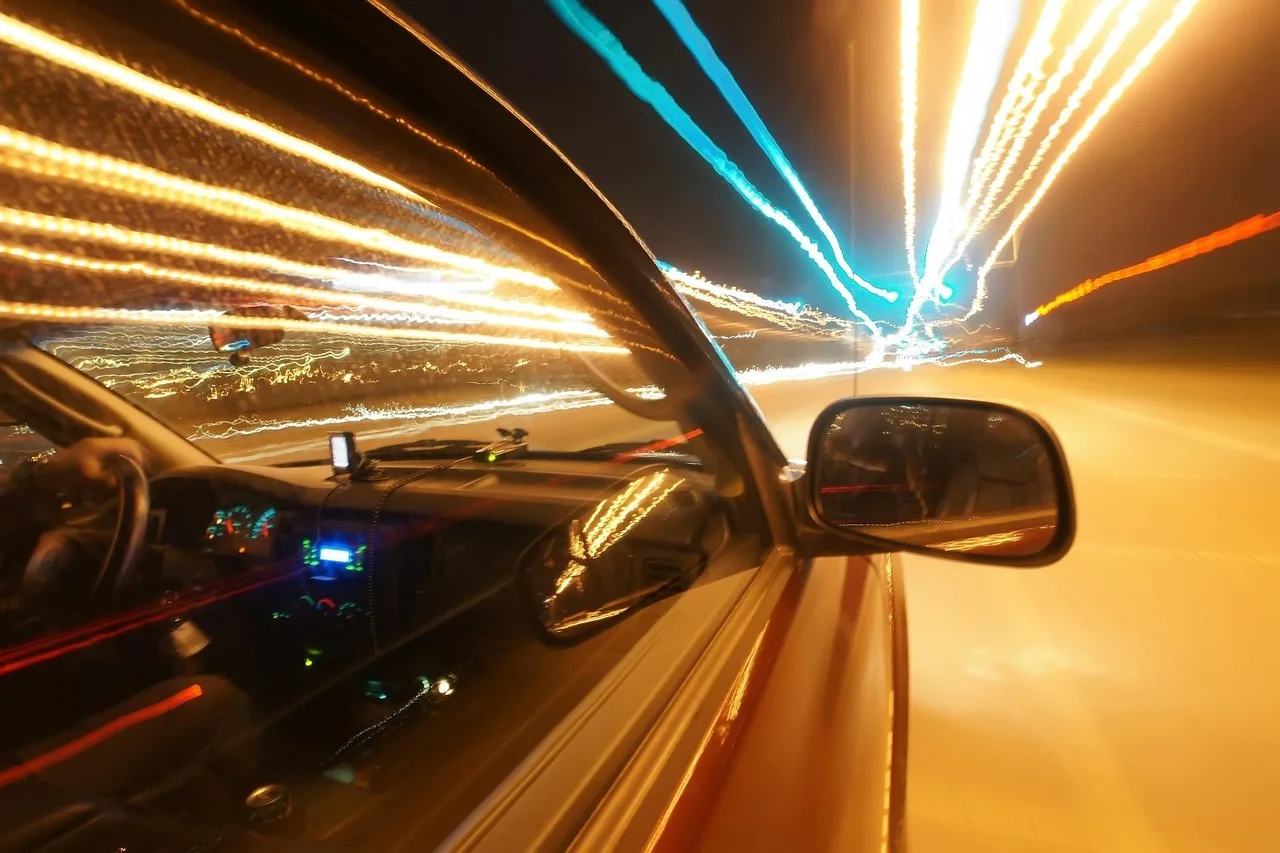 Car with red tail lights, amber signal, and blue dash indicator at dusk
