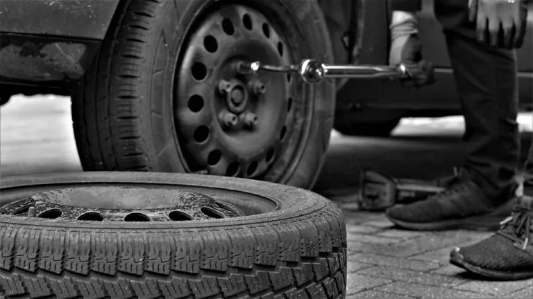 Car tire sidewall with visible scuff and small gouge on a parked vehicle in natural light.