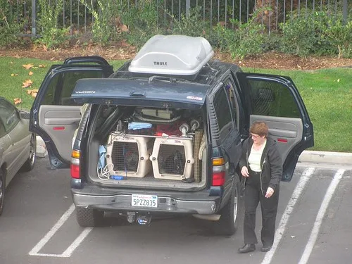 Close-up of a parent folding a third-row seat and securing a booster seat in a family SUV.