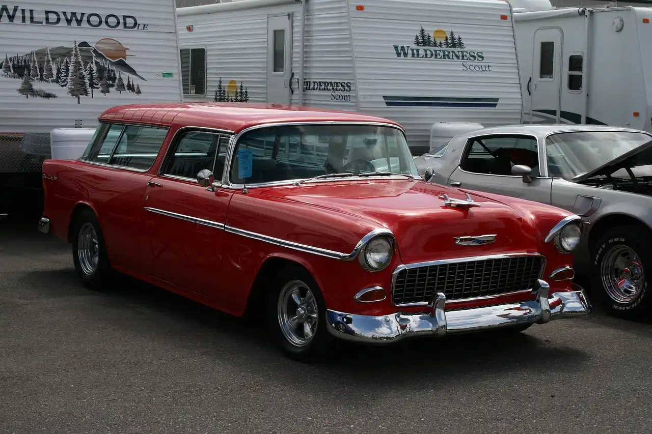 Couple comparing a coupe and a sedan in a sunlit parking lot, with the sedan’s rear door open.