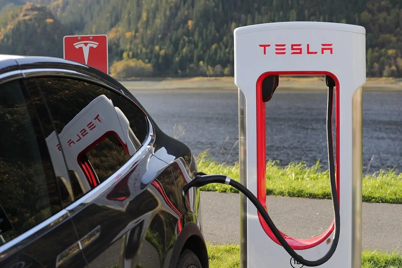 Driver beside an electric car reviewing lease and buy options on a tablet