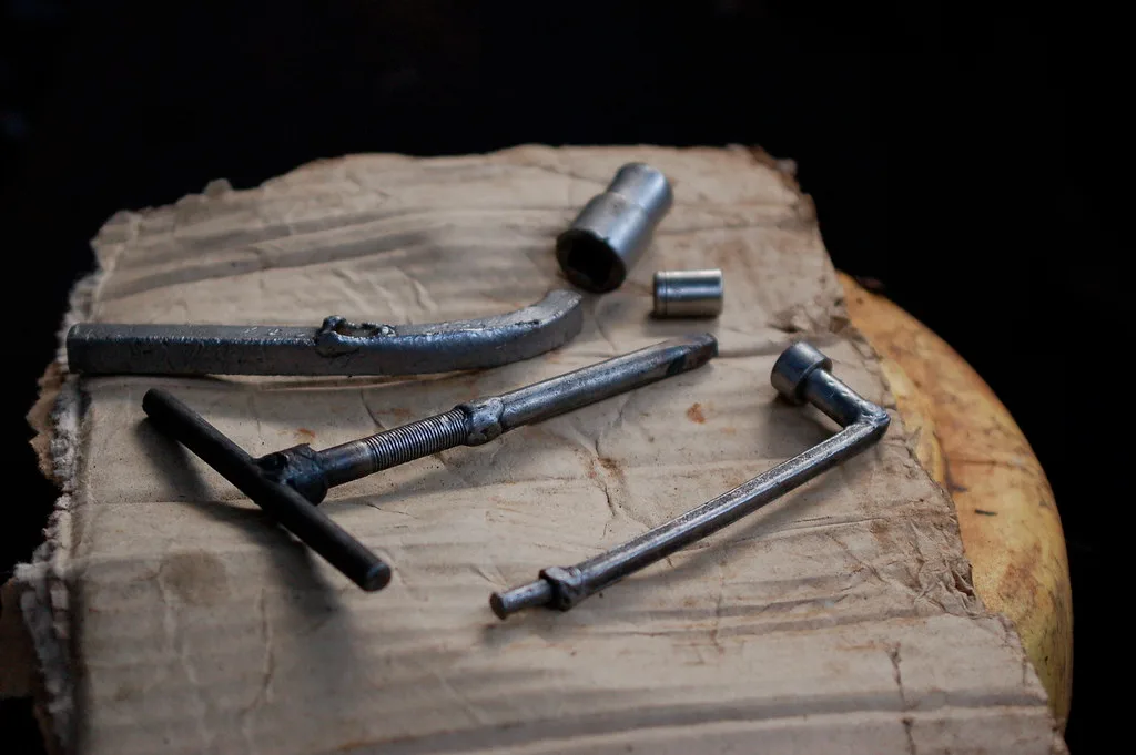 Close-up of a removed cylinder head beside engine block parts on a workbench
