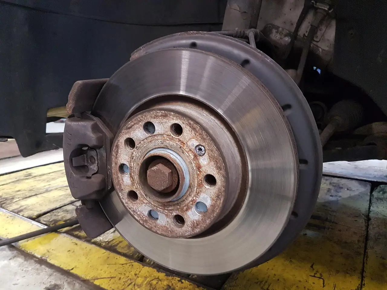Ford brake pads and rotor inspection beside a front wheel in natural daylight