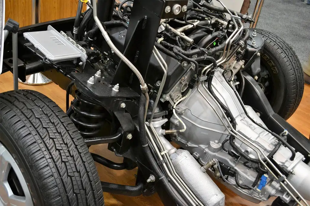 Ford sedan in a repair shop while a mechanic and customer review an itemized service estimate