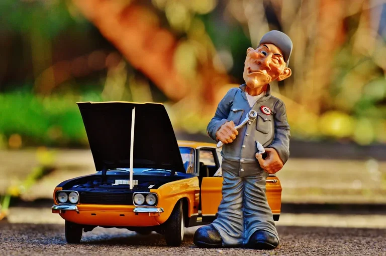Ford SUV in a repair shop with a mechanic beside it and maintenance tools nearby