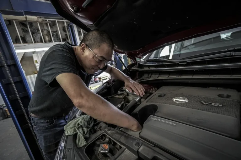 Mechanic and customer beside a white Honda Civic in a daylight auto service garage