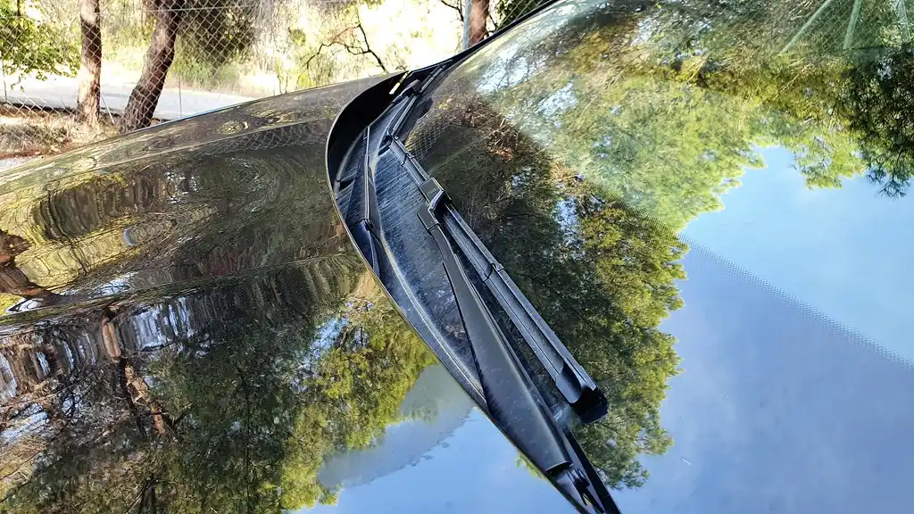 Honda Civic owner checking worn windshield wiper blades in rainy light
