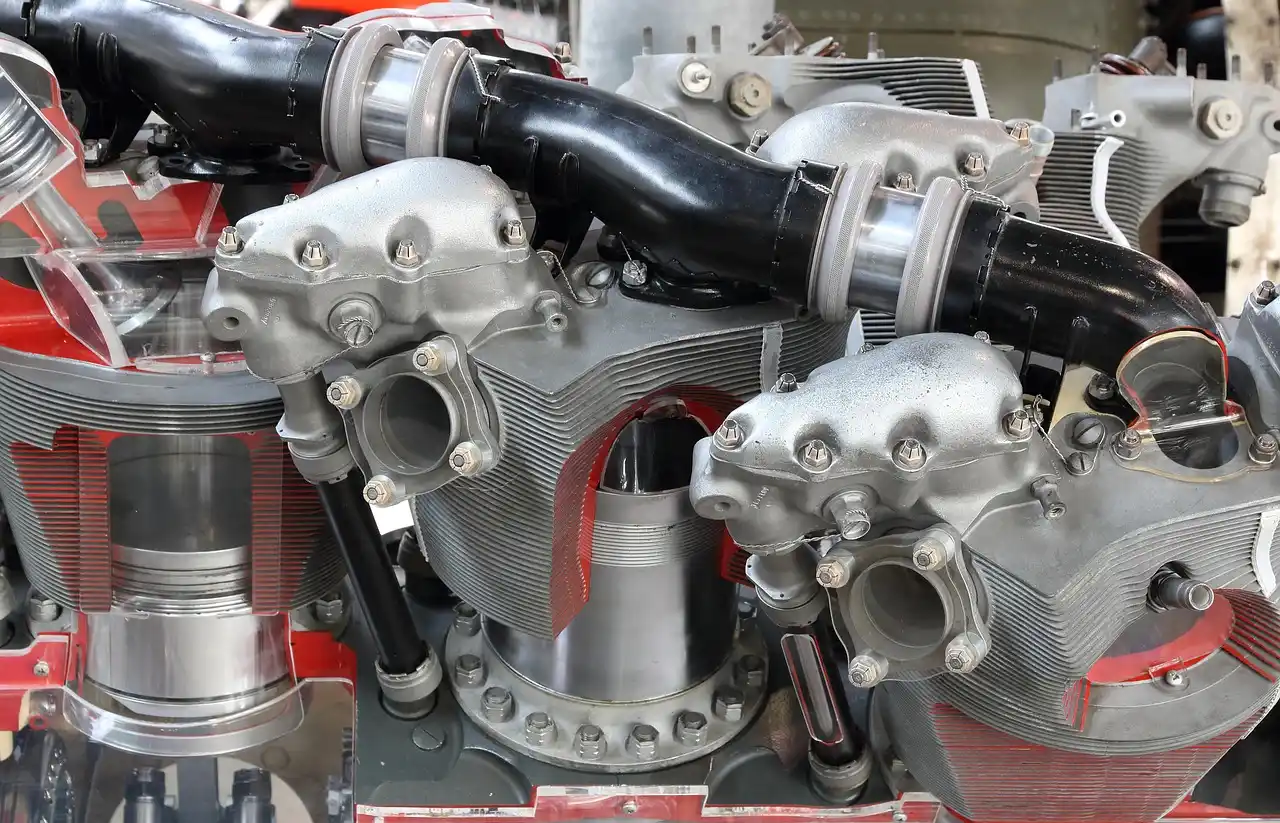 Car engine cylinder head on a workbench beside valves and gasket surfaces in natural light