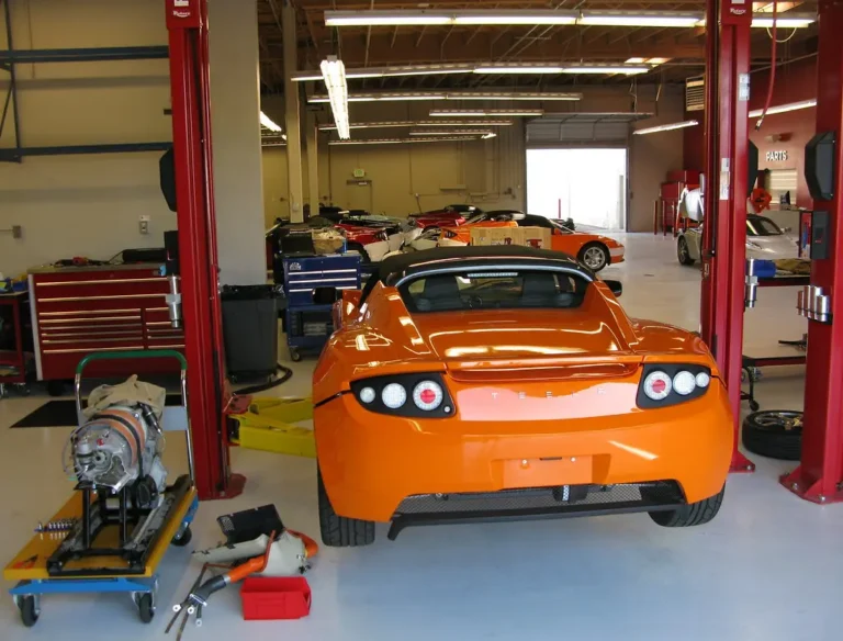 Mechanic diagnosing a car electrical issue with a multimeter under an open hood