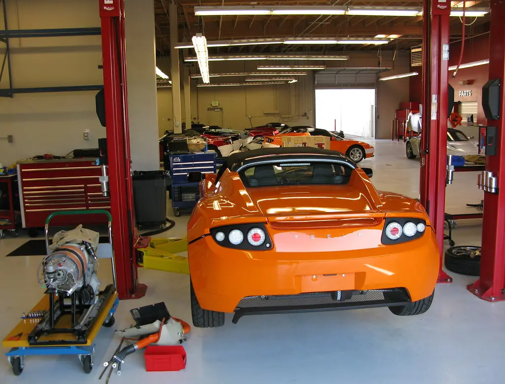 Mechanic diagnosing a car electrical issue with a multimeter under an open hood