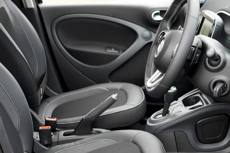 Person wiping a leather car seat with a microfiber cloth in natural light