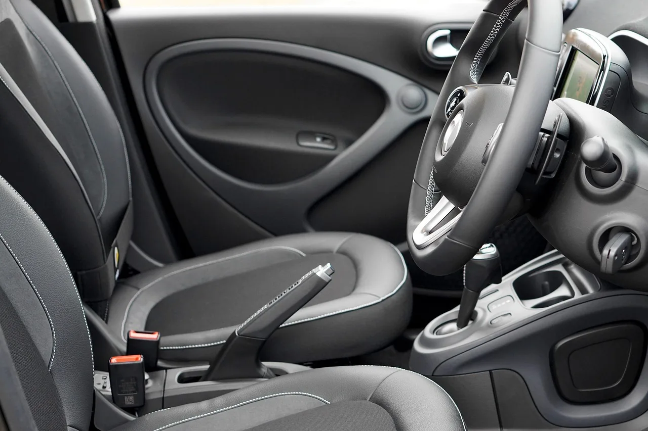 Person wiping a leather car seat with a microfiber cloth in natural light