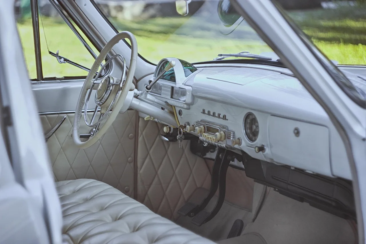 Mechanic inspecting a car accelerator pedal and footwell in natural light