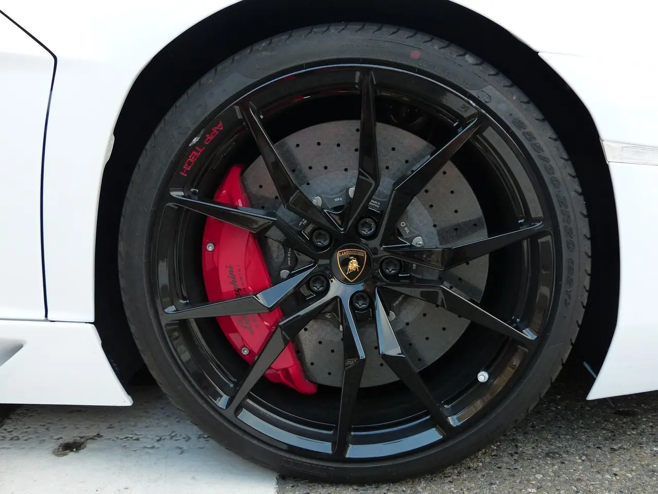 Homeowner checking car brakes with wheel off, showing rotor, caliper, and brake pad in daylight