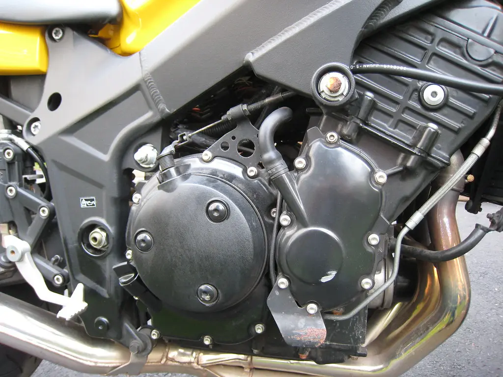 Mechanic checking an engine bay with an oil pressure gauge in a driveway